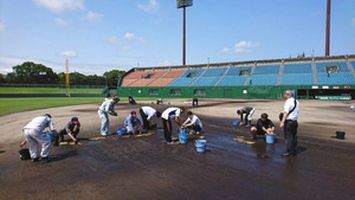 グラウンドの水たまりをぞうきんで搾り取る様子